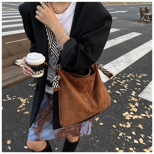 Brown suede tote bag featuring a striped rope knot strap in an autumn street setting