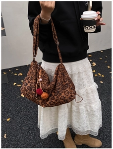 Detail shot of leopard print canvas hobo bag with red and orange pompom accents