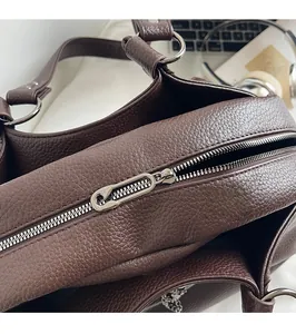 Detail of cross-body bag silver zipper with pin-style puller and lychee texture