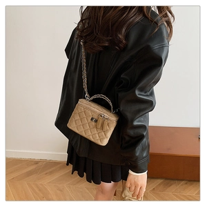 Close-up of quilted crossbody bag with gold chain strap worn by model in room