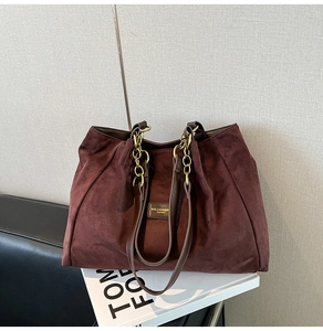 Detail view of large burgundy tote bag with gold chain and premium suede texture