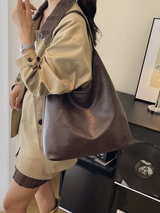 Deep brown faux leather tote bag with large capacity, shown on model wearing trench coat
