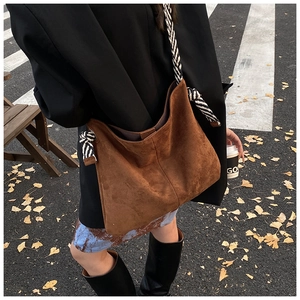 Detail of vintage brown suede tote bag with black and white striped rope knot strap