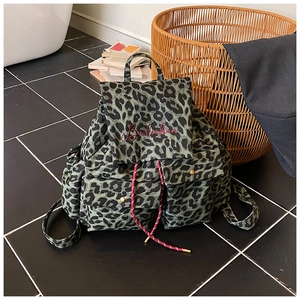 Detail of green leopard canvas backpack showing red embroidery and drawstring closure