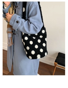 Détail d'un grand sac cabas en peluche noir à pois blancs porté par un mannequin en manteau