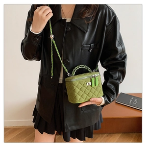 Close-up of green quilted suede box bag with chain strap and silver dual zippers