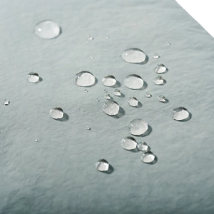 Detail showing waterproof performance with water droplets on light grey-green fabric