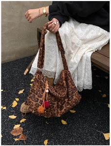 Close-up of leopard print canvas tote bag with soft pompom charm in autumn setting