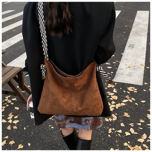 Brown suede tote bag detail featuring a distinctive black and white striped rope shoulder strap