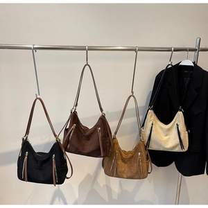 Detail of four hobo shoulder bags in suede finish with vertical zipper accents
