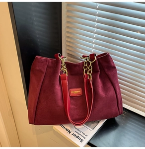 Close-up of burgundy suede tote bag featuring metallic chain straps and premium texture
