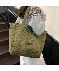 Detail of army green leopard print tote bag featuring black label and green ribbon