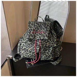 Detail view of leopard print canvas backpack with red drawstring and brand embroidery