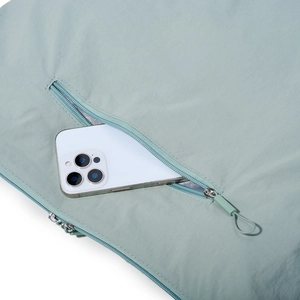 Close-up of light green waterproof nylon tote bag with zipper pocket and smartphone reference