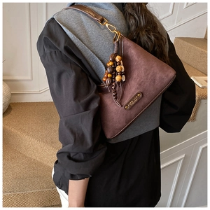 Close-up of brown suede shoulder bag featuring ethnic beads and a vintage metal clasp