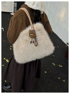 Cream plush tote bag with braided handles and owl charm shown on a model in autumn