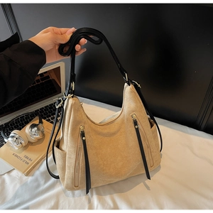 Detailed macro view of khaki suede hobo bag with vertical zippers and long black strap