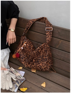 Detail of leopard print tote bag with plush charm and wide strap on autumn park bench