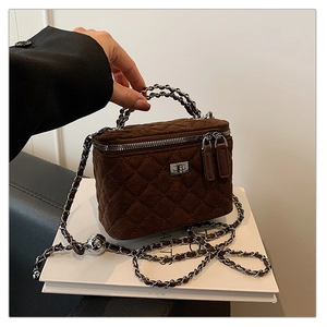 Macro detail of brown quilted suede vanity bag with silver chain strap and metal lock