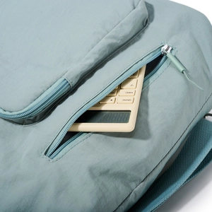 Detailed view of the light blue nylon tote bag with functional front zipper pocket