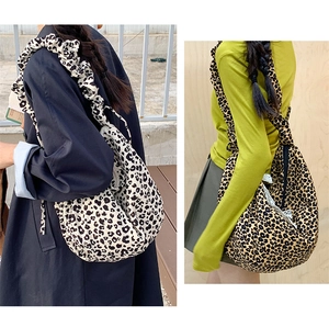 Detail view of large leopard print tote bag featuring a decorative scrunchie shoulder strap