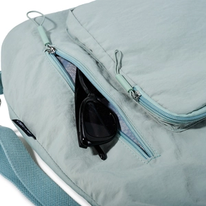 Detail view of light green wrinkled nylon fabric and side brand label on tote bag