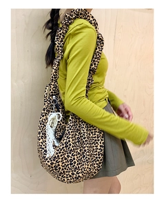 Detailed side view of leopard print tote bag with ruffled strap and tassel accent