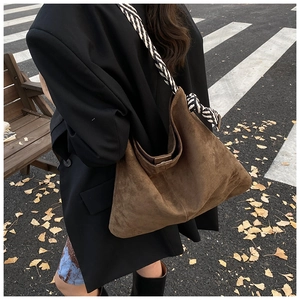 Detail of a large brown matte hobo bag with a distinctive black and white woven strap
