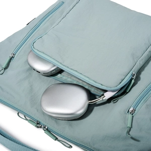 Detail of light blue nylon tote bag showing side pocket with silver headphones stored inside