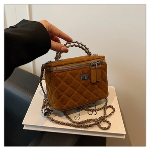 Detailed view of the brown quilted vanity bag with silver turn-lock and chain strap