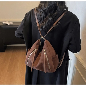 Detail of dark brown faux suede backpack featuring dual zipper accents and soft texture