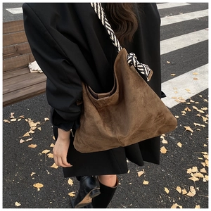 Close-up of brown suede hobo bag with geometric black and white woven shoulder strap