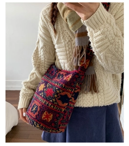 Détail d'un sac seau en peluche aux motifs ethniques sur un pull en maille beige