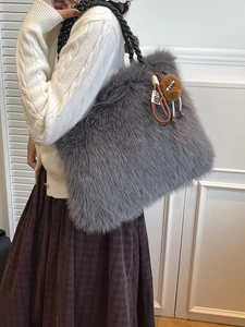 Faux fur tote bag with braided handles and pom-pom charm shown on a female model