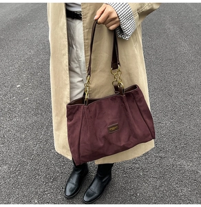 Detail view of burgundy suede tote bag featuring gold hardware and chain shoulder strap