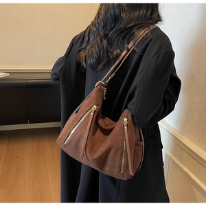 Detailed close-up of a large brown suede hobo bag with metal zipper and leather strap