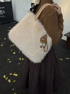 Furry cream-white tote bag with woven handles and a cute plush charm on a model's shoulder