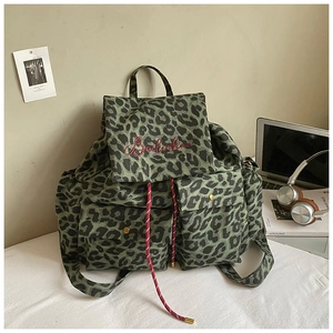 Detailed close-up of leopard print canvas backpack with red embroidery and drawstrings