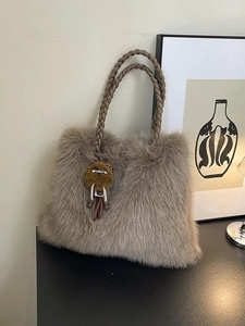 Khaki faux fur handbag with thick woven handle and cute bear plush charm on a table