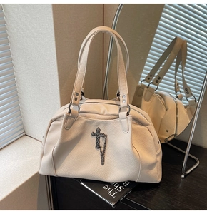 Detail of off-white lychee grain leather bag featuring silver gothic cross and chain decor