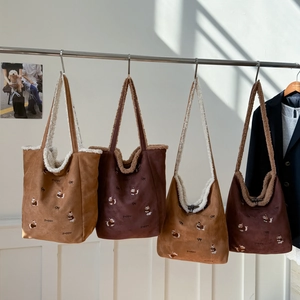 Detail of corduroy and shearling tote bags with puppy embroidery on metal hangers