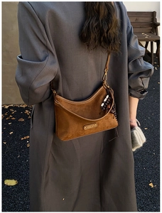Gros plan d'un sac bandoulière en daim marron en demi-lune avec franges à perles sur manteau
