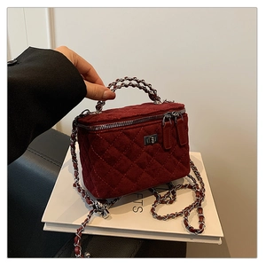 Close-up of wine red quilted velvet mini box bag with chain strap and dual zippers