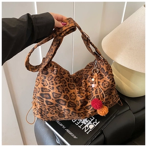 Detailed close-up of leopard print tote bag with orange pompom and wide strap