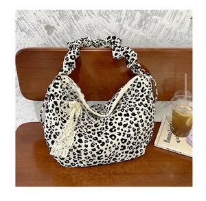Close-up of leopard print tote bag featuring ruffled handles and white lace fringe charm