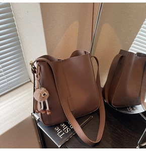 Détail du sac seau marron en cuir grainé avec un pendentif en peluche mignon