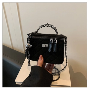 Close-up of black quilted velvet vanity bag with silver chain handle and metal twist lock