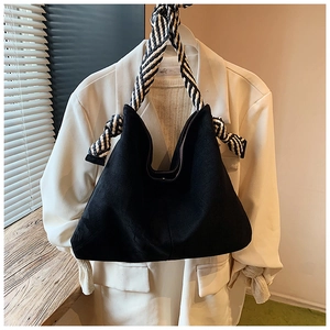 Close-up of black frosted tote bag with a striped braided shoulder strap and large knot detail