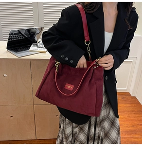 Detailed view of a burgundy suede tote bag styled with a professional black blazer