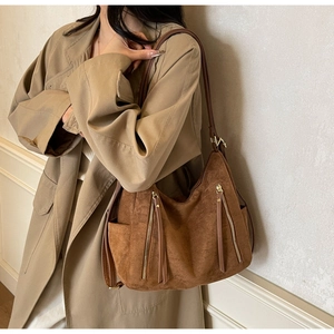 Detail of dark brown faux suede tote bag featuring metallic zippers and fringe tassels